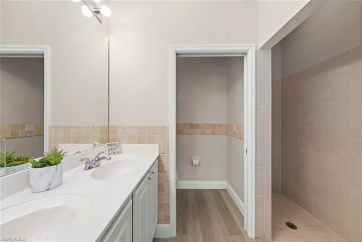 Primary bathroom with dual sinks, a tile shower