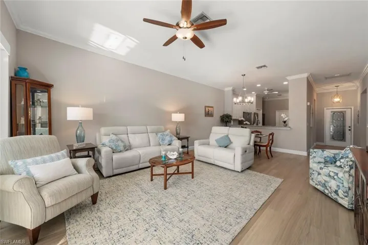 Living area with crown molding, a ceiling fan, vinyl plank flooring, and a chandelier