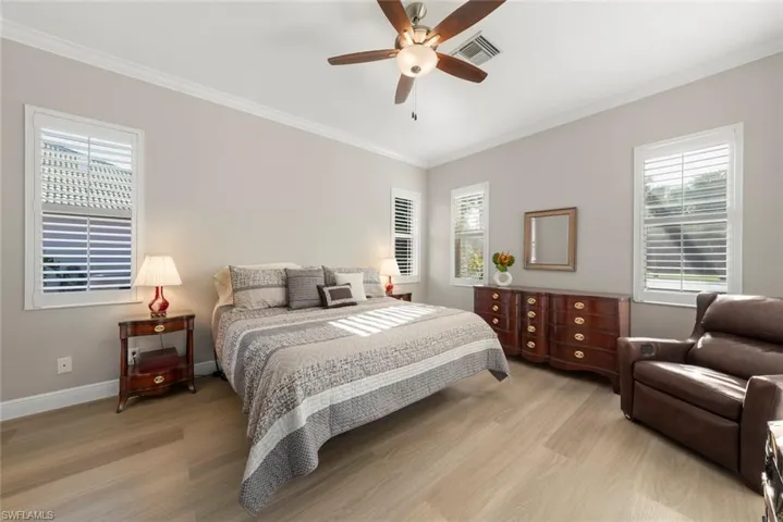 Bedroom featuring crown molding, light wood-type flooring, and a ceiling fan