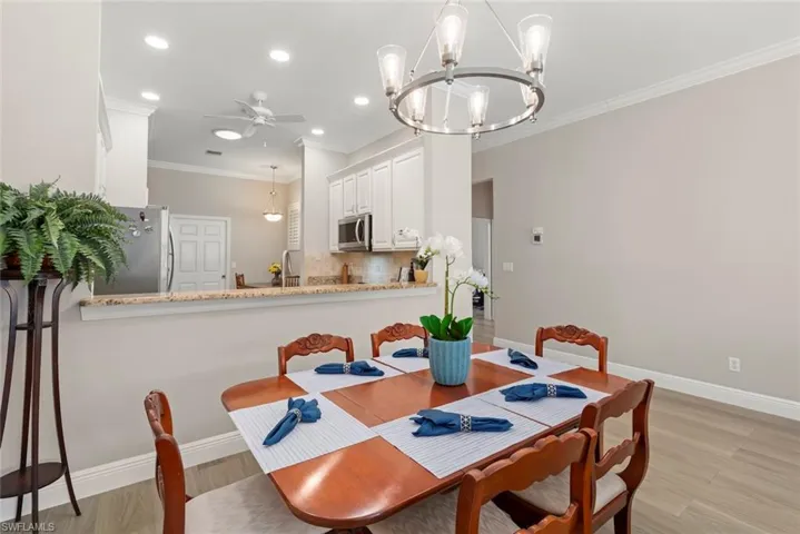 Dining area featuring crown molding, a ceiling fan, light wood-style floors, a chandelier, and recessed lighting