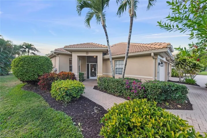 Attached Villa, with a two car garage, stucco siding, brick paver driveway, and a tiled roof