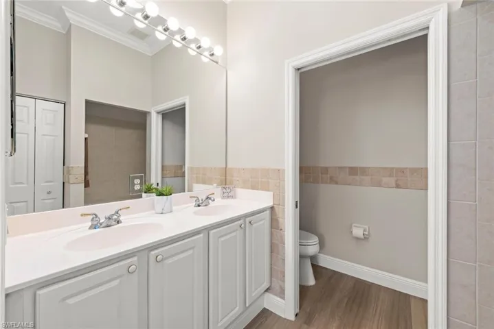 Primary bathroom featuring double vanity, crown molding, wood finished floors.