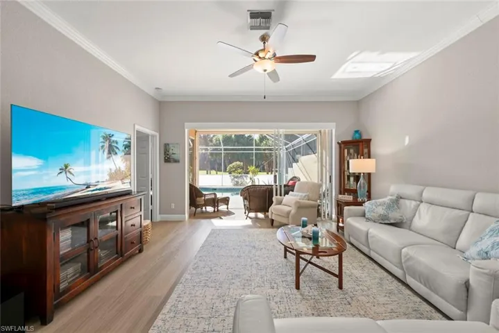 Living room featuring a sunroom, crown molding, light wood-type flooring, and ceiling fan