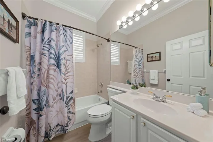 Full bath with shower / bath combo, vanity, ornamental molding, and dark wood-style floors