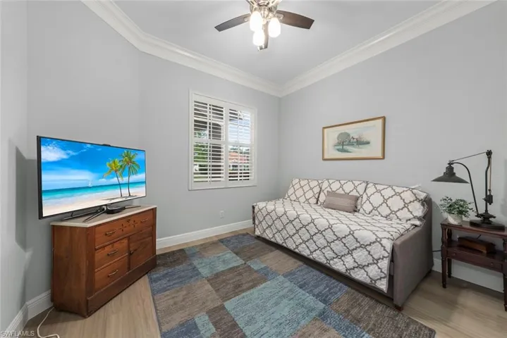 Guest bedroom with crown molding, a ceiling fan, and light wood-style floors