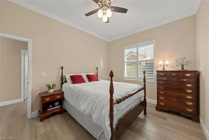 Bedroom with light wood finished floors, ornamental molding, and ceiling fan