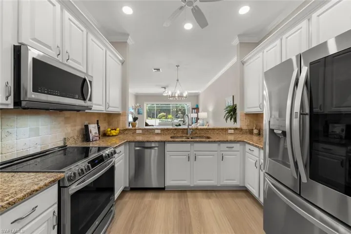 Kitchen featuring Stainless Steel appliances, white cabinets, crown molding, a chandelier, and light wood finished floors