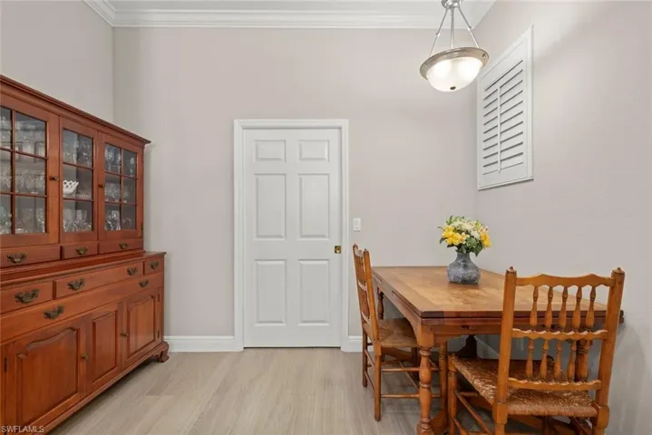 Dining area with light wood finished floors and crown molding