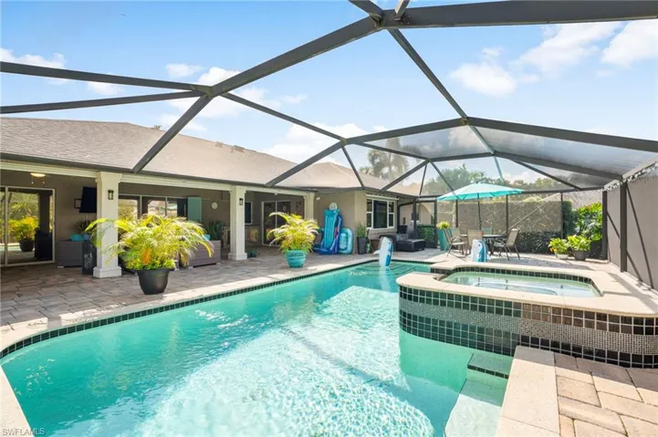 View of pool featuring glass enclosure, a patio area, and an in ground hot tub