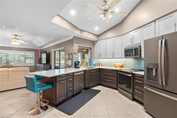 Newly renovated kitchen is an extension from the family room and features new slate counter, GE Profile appliances, beige upper and brown lower cabinets, recessed ceiling and with breakfast bar.