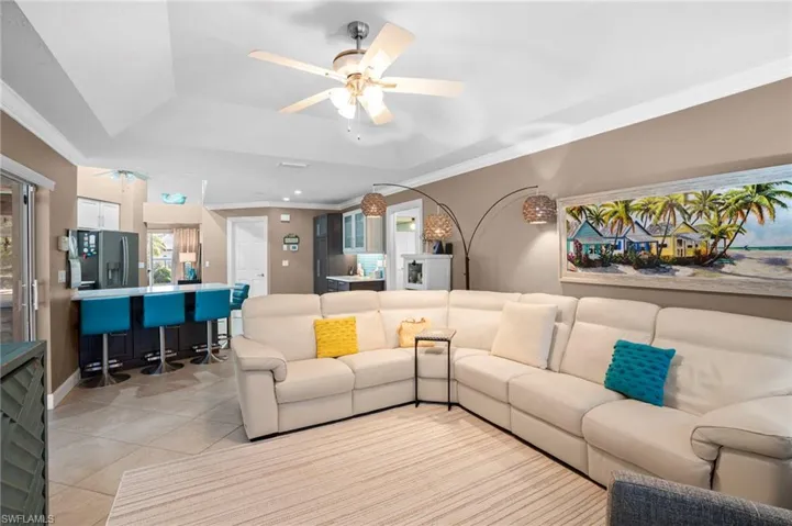 Family room with tray ceiling offers substantial lighting and natural lighting from sliding glass doors and large windows overlooking pool area.