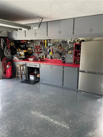 Garage featuring a workshop area and refrigerator/freezer.
