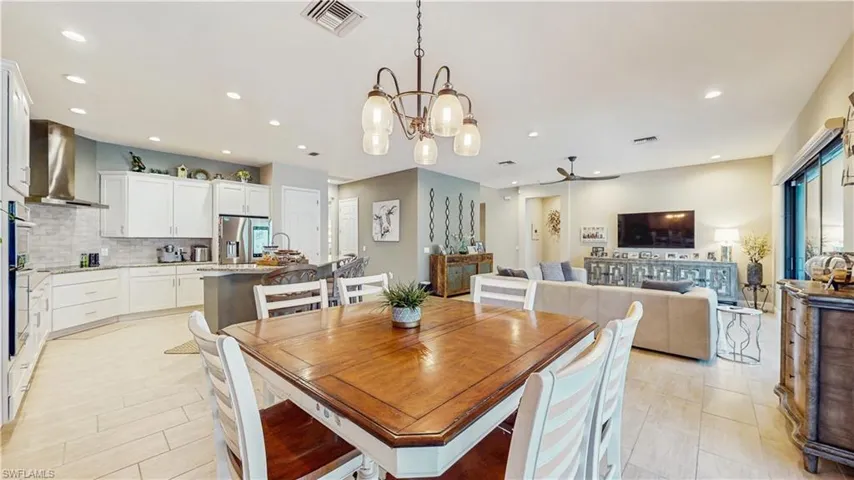 NOOK SITTING AREA WITH 8 CHAIRS, LIGHTING, VIEW OF FAMILY ROOM WITH HUGE SECTIONAL SOFA & KITCHEN W LIGHT COLOR KITCHEN CABINETS