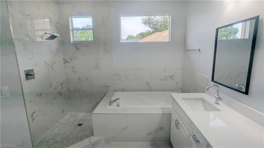 Bathroom with independent shower and bath, a wealth of natural light, and vanity