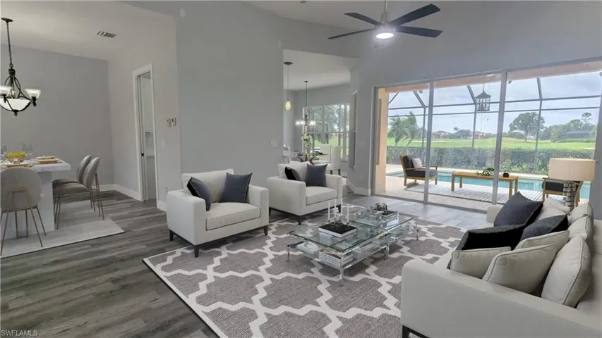 Living room with ceiling fan with notable chandelier, dark wood-type flooring, and lofted ceiling