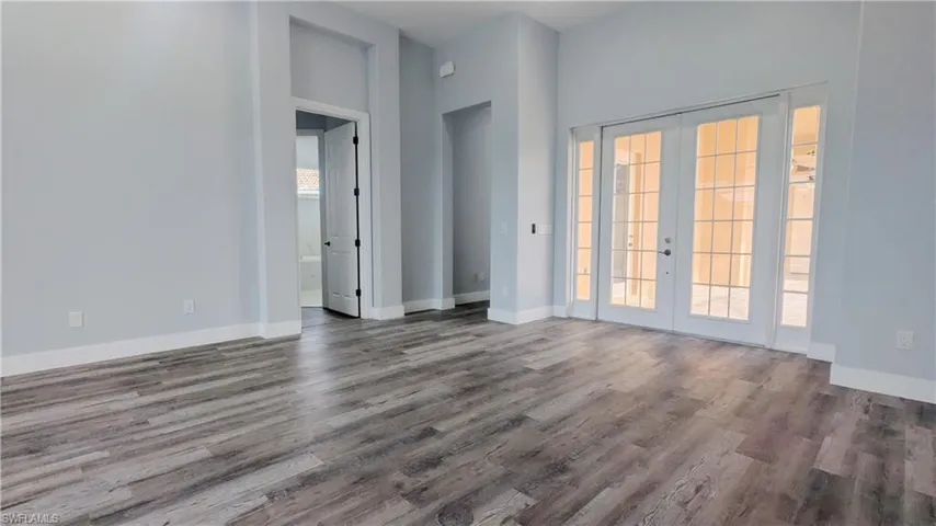 Spare room featuring plenty of natural light, dark wood-type flooring, and french doors
