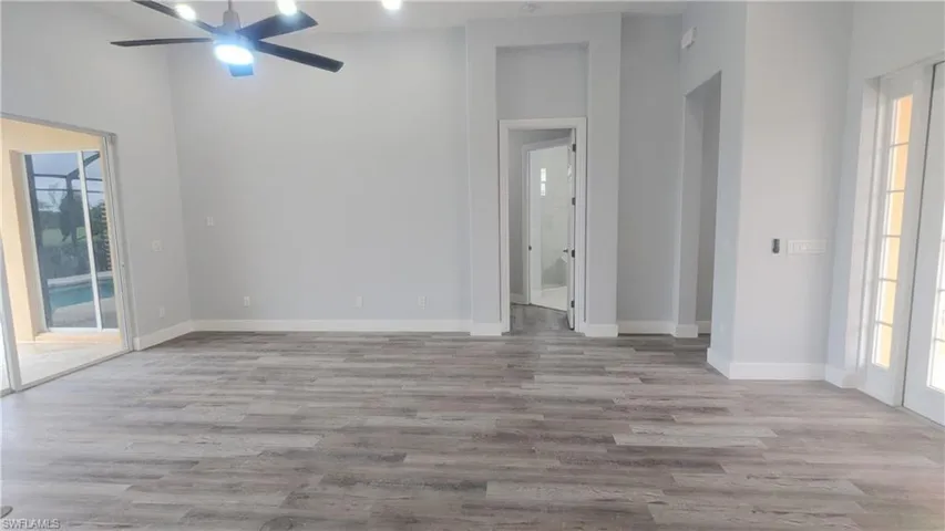 Spare room with a wealth of natural light, high vaulted ceiling, ceiling fan, and light wood-type flooring