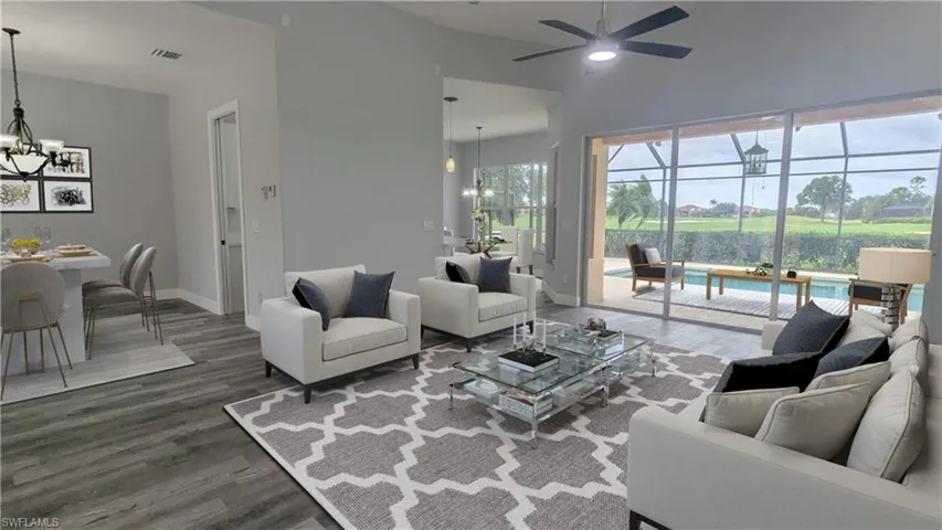 Living room with dark wood-type flooring, vaulted ceiling, and ceiling fan with notable chandelier