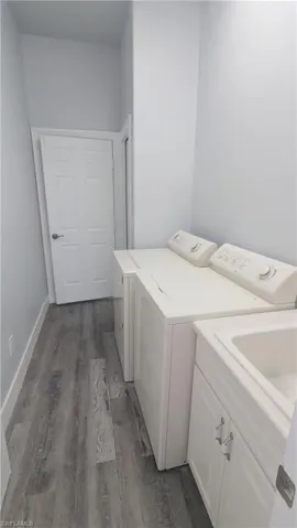Washroom featuring dark wood-type flooring, cabinets, and independent washer and dryer