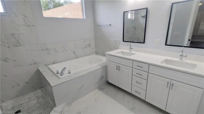 Bathroom featuring vanity and tiled bath