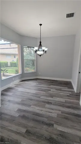 Unfurnished dining area featuring dark wood-type flooring and an inviting chandelier