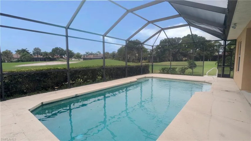 View of pool with a yard and glass enclosure