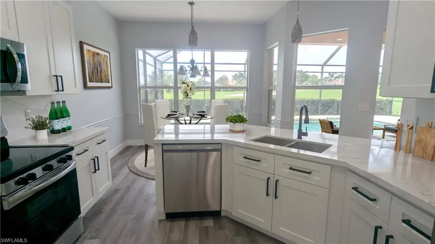 Kitchen with white cabinets, stainless steel appliances, sink, and a healthy amount of sunlight