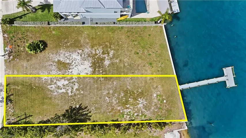 Aerial view of property and surrounding area with a nearby body of water and property parcel outlined - Virtually Edited Image