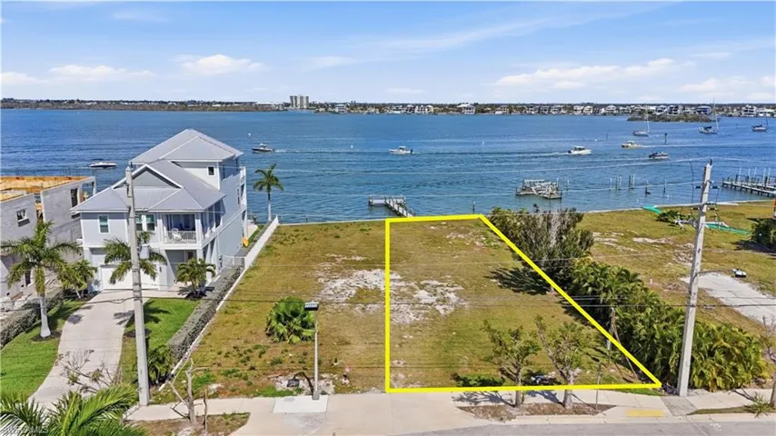 Aerial overview of property's location with property parcel outlined and a nearby body of water - Virtually Edited Image