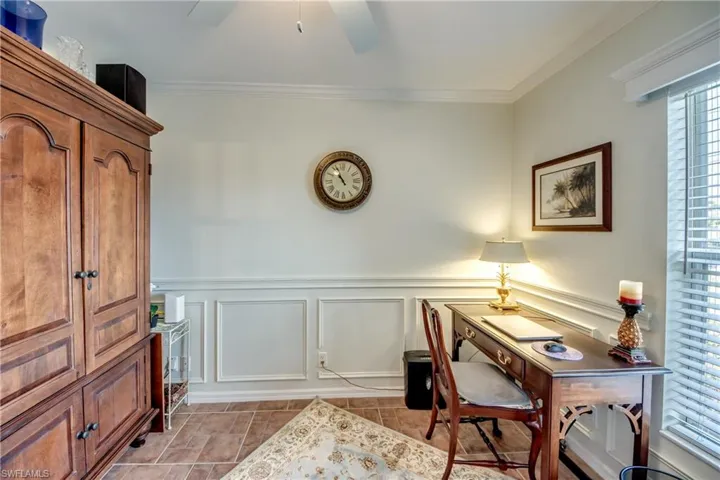 Home office featuring crown molding, a wainscoted wall, ceiling fan, and a decorative wall