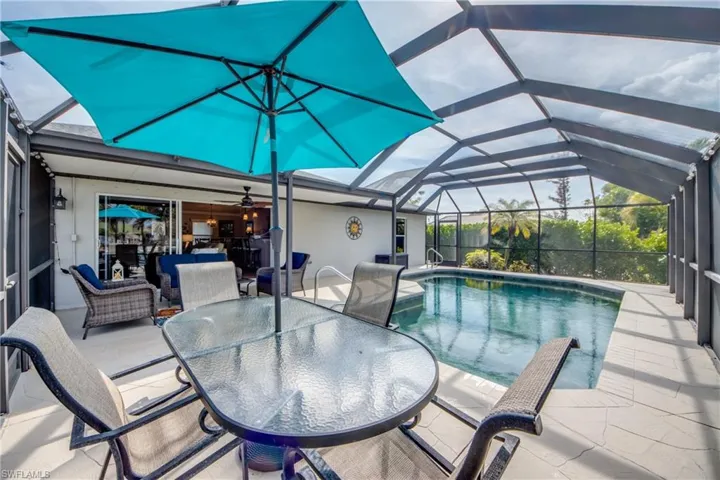 Swimming pool featuring a sunroom, outdoor dining space, and glass enclosure