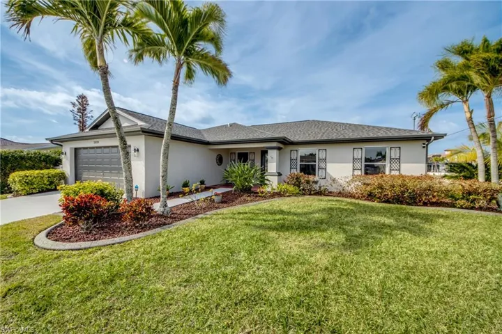 Ranch-style home with stucco siding, a garage, a front lawn, and driveway