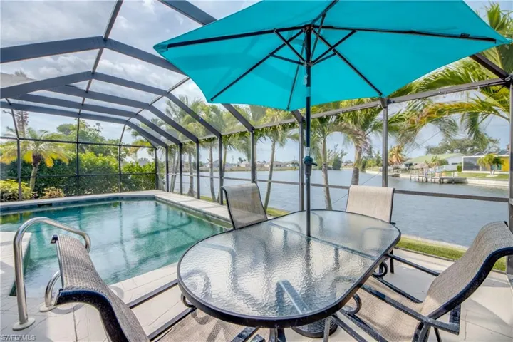 Swimming pool with a sunroom, a lanai, a patio area, outdoor dining space, and a water view