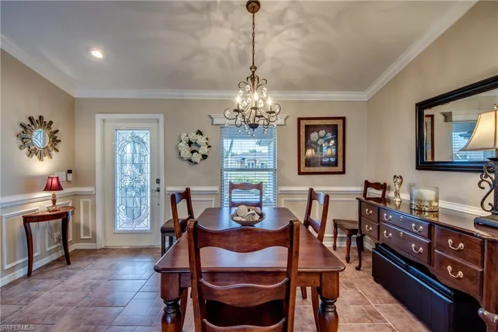 Dining space featuring crown molding, suspended lighting, a wainscoted wall, and a decorative wall