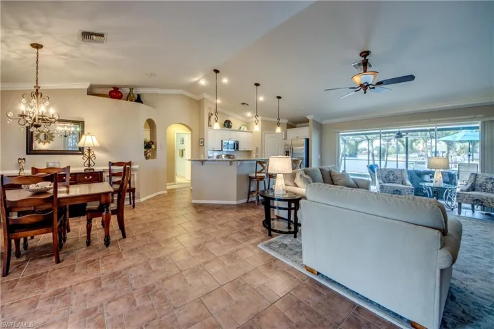 Living area with crown molding, hanging lights, arched walkways, lofted ceiling, and a ceiling fan