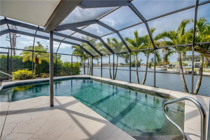Outdoor pool with glass enclosure, a sunroom, and a patio