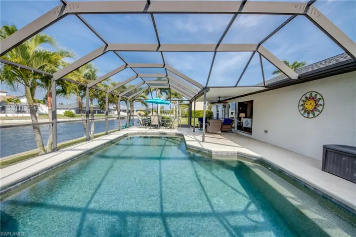 Outdoor pool featuring a lanai, a sunroom, a patio area, a water view, and an outdoor living / dining area