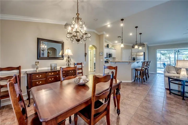 Dining area with vaulted ceiling, hanging lights, crown molding, and arched walkways