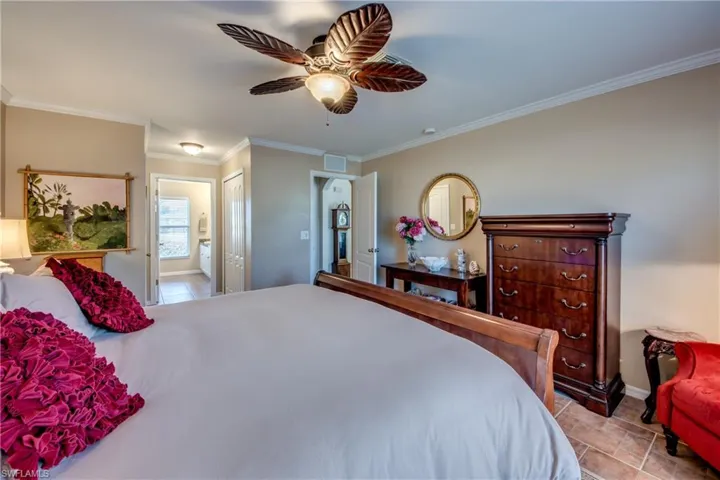 Bedroom featuring ornamental molding, ensuite bath, a ceiling fan, and a closet