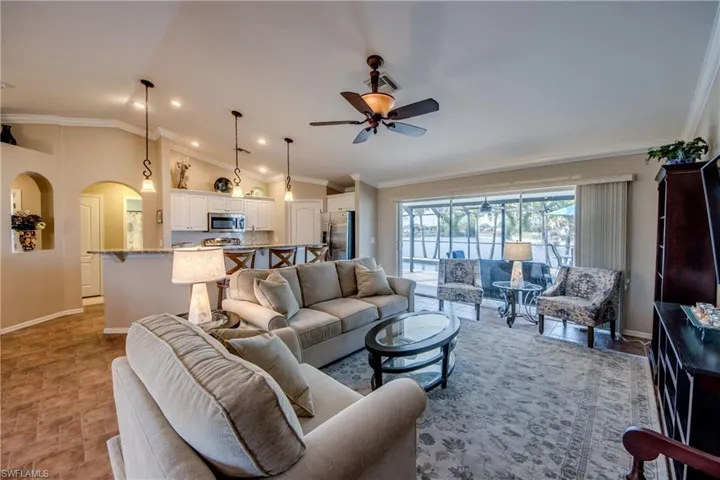 Living area featuring ornamental molding, arched walkways, ceiling fan, and lofted ceiling