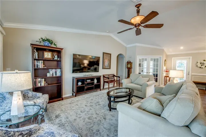 Living area with lofted ceiling, ornamental molding, arched walkways, french doors, and ceiling fan