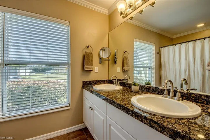 Full bath with crown molding, double vanity, and curtained shower