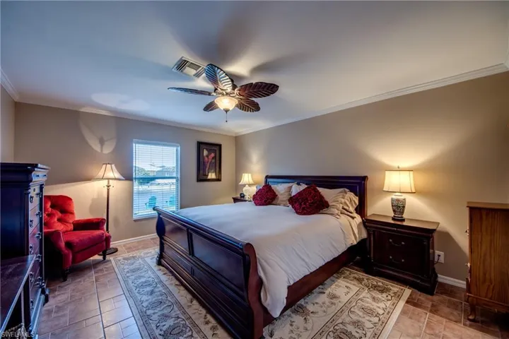 Bedroom featuring crown molding, stone finish floors, and a ceiling fan