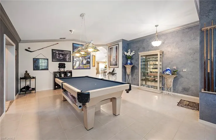 Rec room with crown molding, billiards table, arched walkways, and light tile patterned floors