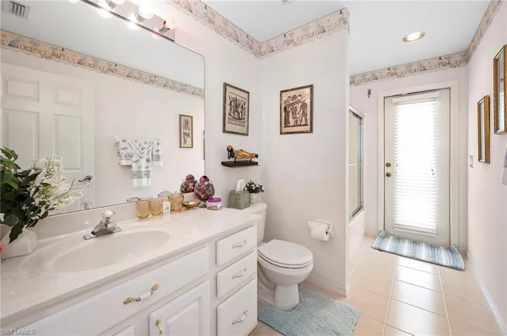 Bathroom featuring enclosed tub / shower combo, vanity, and light tile patterned floors