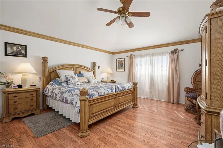 Bedroom featuring ceiling fan, light wood-style floors, and ornamental molding
