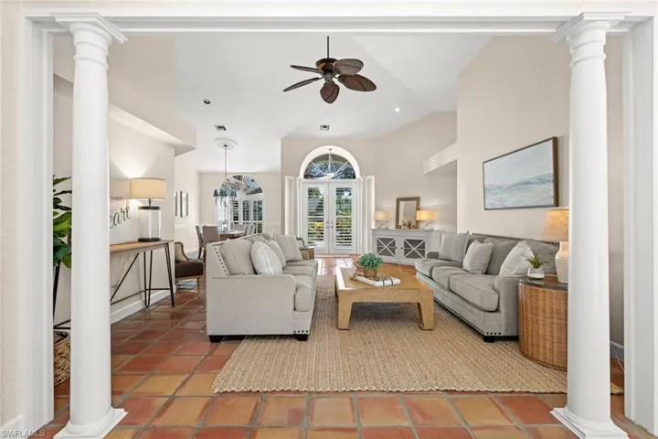 Living area with decorative columns, a ceiling fan, and high vaulted ceiling