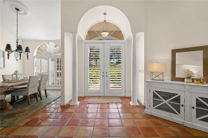 Foyer entrance with french doors, a chandelier, plenty of natural light, and light tile patterned flooring