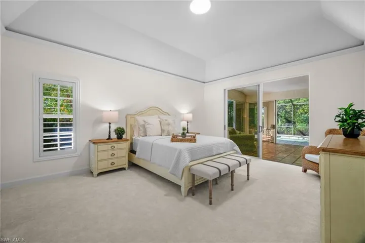 Carpeted bedroom with access to exterior, multiple windows, and a raised ceiling