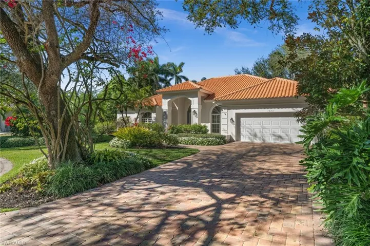 Mediterranean / spanish home featuring stucco siding, a tile roof, a garage, decorative driveway, and a front lawn
